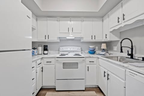 Modern all-white kitchen featuring stylish cabinetry, countertops, and appliances, offering a clean and functional space for cooking and dining.