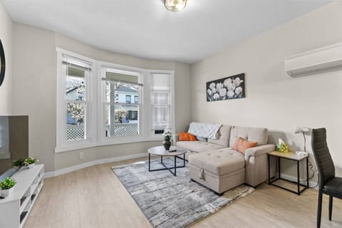 Bright and inviting living room with a sectional sleeper sofa and three oversized windows that flood the space with natural sunlight.