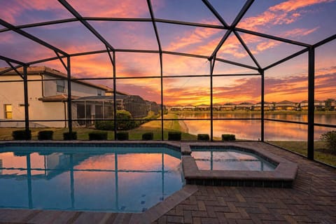 Relax by the screened pool and spa with lake views at sunset.