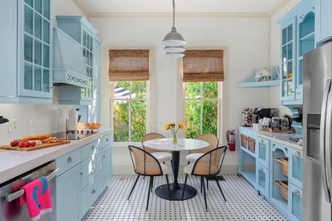 This cheerful kitchen features pastel blue cabinetry, natural wood accents, and a cozy dining nook bathed in sunlight. The perfect blend of style and practicality.