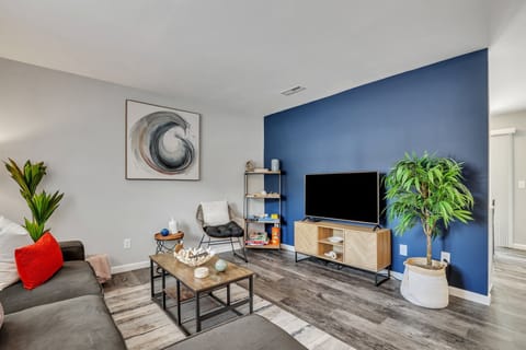 Sleek flat-screen TV with bold navy accent wall — unwind after a day exploring Historic Downtown Charleston (20 min away)