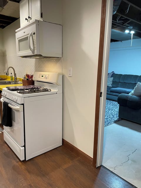 Doorway to bonus basement room with sectional & view of basement kitchen.