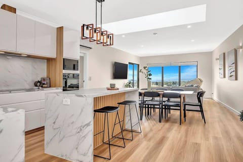 Upstairs, a beautifully designed open-plan layout bathed in natural light from expansive windows creates the perfect setting for entertaining.