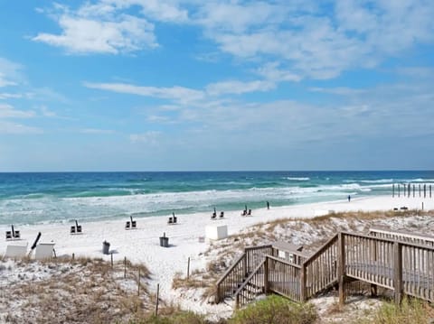 Pristine white sand beach with turquoise waters and wooden boardwalk access, perfect for peaceful coastal getaways.