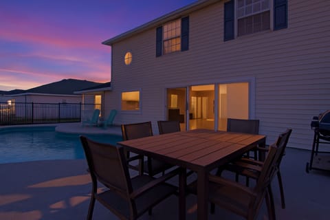 Evening by the private pool and patio. Enjoy outdoor dining and sunset views from this spacious screened backyard featuring comfortable seating and a grill, perfect for relaxing or entertainin