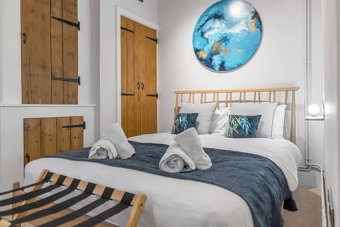 A cozy bedroom with a comfortable double bed, fresh linens, and soft towels. Warm lighting and neutral tones create a relaxing ambiance, perfect for unwinding after a day in Norwich.