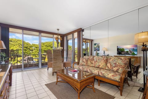 Relax in your tropical living room with lush views through floor-to-ceiling windows and access to a private balcony overlooking vibrant greenery—perfect for unwinding in island comfort.