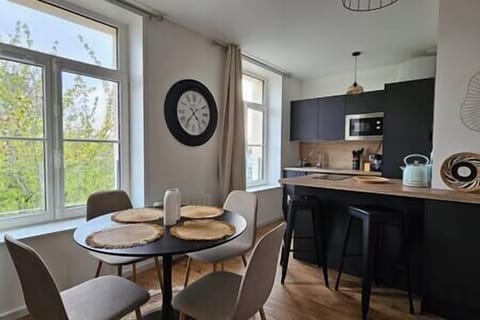 Espace salle-à-manger dans le salon, avec une table et quatre chaises, ouvert sur la cuisine. 