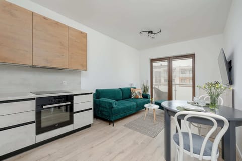 A modern kitchen with wooden cabinets and built-in appliances. A dining table with chairs is placed conveniently nearby.