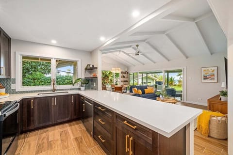 Modern kitchen with dark wood cabinets, white quartz countertops, and open-concept design.