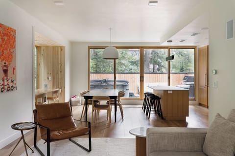 Modern open-concept living, dining, and kitchen area with warm wood accents and seamless deck access.