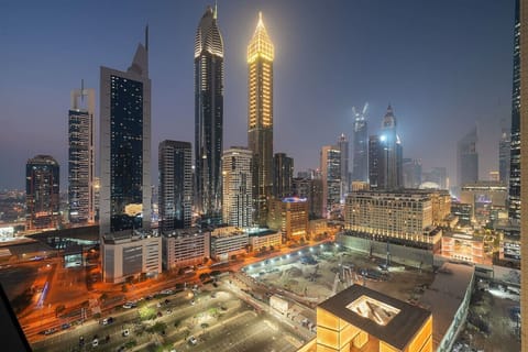 Night skyline view of illuminated skyscrapers and city streets below.