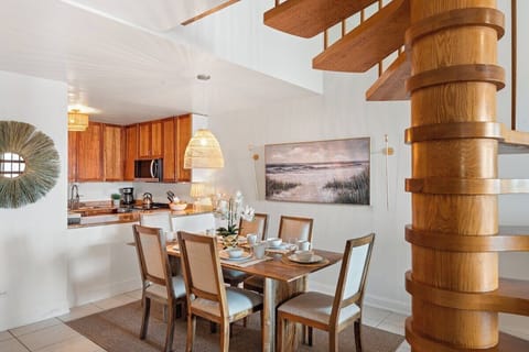 Bright dining area with island‑inspired textures, lush greenery accents, and a warm, airy atmosphere.