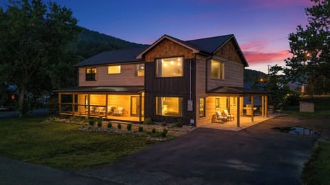 Beautiful two-story cabin illuminated at dusk, showcasing cozy outdoor seating.
