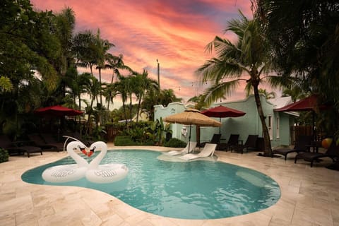 Relax in this peaceful oasis as the sky turns vibrant hues, with swan floats and loungers ready for the perfect evening under the palms.