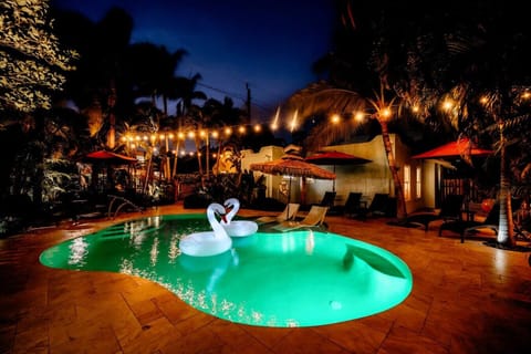 Enjoy the tranquil pool illuminated under string lights, with swan floats and tropical vibes creating a serene evening atmosphere.