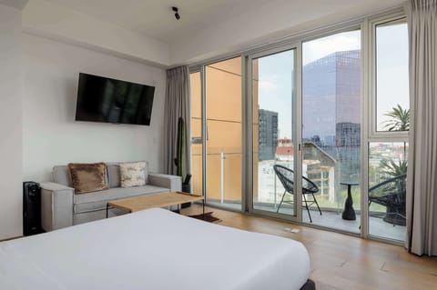 Bright loft-style bedroom with floor-to-ceiling windows and beautiful city views.
