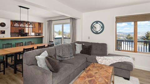 - Spacious living room with plush sectional sofa for group relaxation   - Large windows bring in natural light and mountain views   - Open layout flows into dining and kitchen for social gatherings