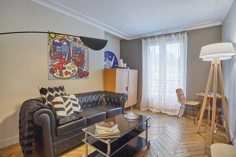 Salon avec canapé, table basse, coin bureau et TV