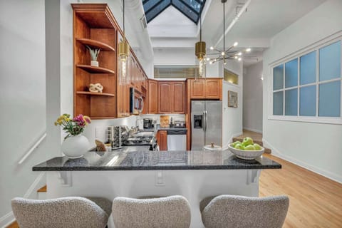Stylish and inviting kitchen featuring rich wood cabinetry, polished granite countertops, and a skylight that bathes the space in natural light. Ideal for savoring meals or a morning coffee at the comfortable breakfast bar!