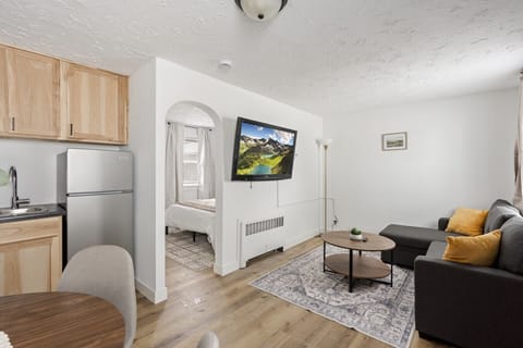Integrated dining space offering a neutral-toned sectional and wood-style flooring.