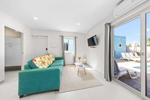 Modern, minimalist apartment featuring a comfortable seating area with a smart TV, air conditioning, and access to an outdoor pool.