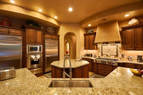 A stunning open-concept chef's kitchen, fully equipped with premium stainless-steel appliances, cooking essentials for your culinary creations, an informal dining table, and a sleek breakfast bar for casual seating.