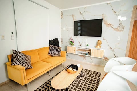 Relax in style with this modern living room featuring a plush yellow sofa, elegant decor, and a large flat-screen TV.