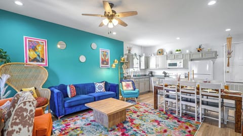 Bright, colorful downstairs living area with cozy seating, vibrant decor, & a fully equipped kitchen