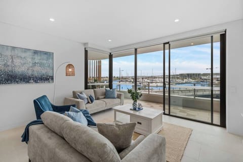 Unwind in the stylish living room, featuring comfortable seating and breathtaking marina views through floor-to-ceiling glass doors.