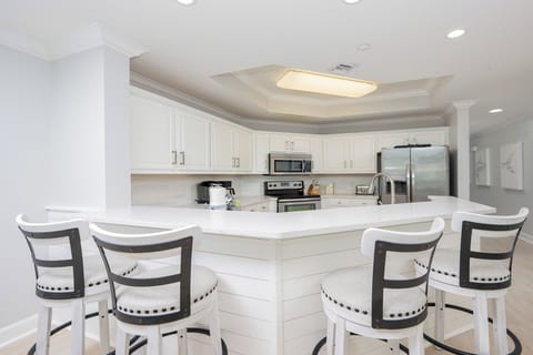 The kitchen features stainless appliances, white cabinets, and a spacious countertop perfect for meal prep and gatherings