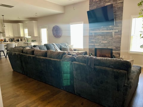 Oversized sectional w/ TV mounted on floor to ceiling stone fireplace 