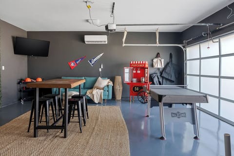 Fun-Filled Game Room with Lounge Area & Garage-Style Door
Vibrant game room featuring a ping pong table, retro arcade game, comfy seating, and wall-mounted TV. Enjoy natural light from the garage-style door, perfect for entertainment!
