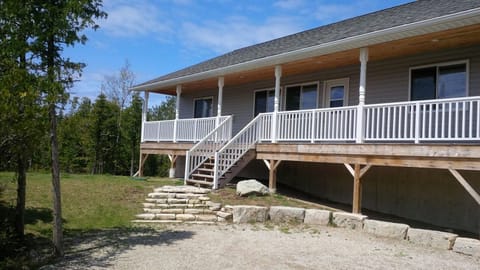 Front of the House – A spacious, private 4-bedroom getaway featuring a charming covered porch, perfect for relaxing and taking in the peaceful surroundings. The large lot offers plenty of space to enjoy nature.