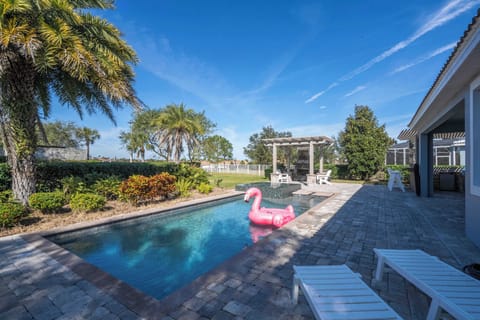 Relax in this private tropical backyard - sparkling pool, paver deck, palm trees, comfy loungers and a playful pink flamingo float, perfect for soaking up the Florida sun.