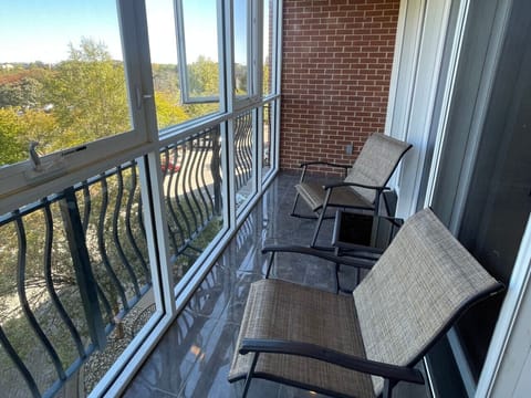 Relax on your private screened balcony with outdoor seating and serene views — an inviting space to enjoy fresh air and unwind during your extended stay at The Gateway Village in Murfreesboro.