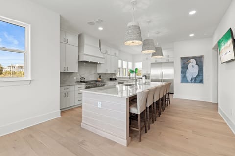 Your spacious chef's kitchen features pristine white cabinetry, gleaming countertops, and a grand island where culinary memories await creation together.