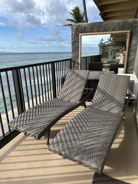 Two lounge chairs on the lanai overlooking the ocean.