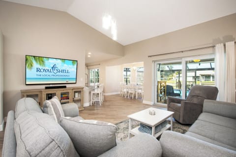 This open-concept living area features comfortable seating, a smart TV, and sliding doors that lead directly to the lanai for easy indoor-outdoor living