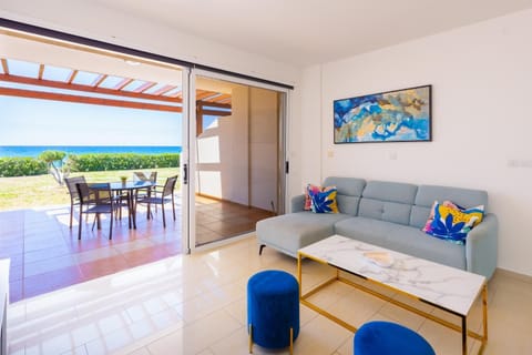 An interior view of a bright, modern living room within the property, seamless leading out to a shaded patio with a panoramic sea view.