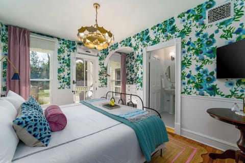 Suite 1: Private entrance with semi-private porch or additional optional entry through hallway, King Anthropologie bed, 50" Smart TV, porcelain tile bath, and option to adjoin with Suite 2. 