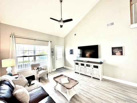 Spacious living room with TV, leather couch, arm chair, board games