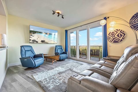 Relax in the modern living room with reclining chairs and a balcony view.