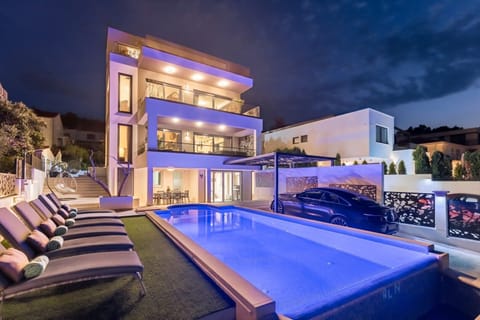 Night view of outdoor heated infinity pool and sun loungers in Luxury Villa Destiny Ciovo 1 with heated pool at the beach