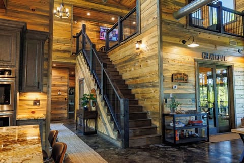 Stunning open-concept cabin interior with wood-paneled walls, a loft area, modern kitchen, and a cozy rustic design. A dream vacation rental with luxury farmhouse style.