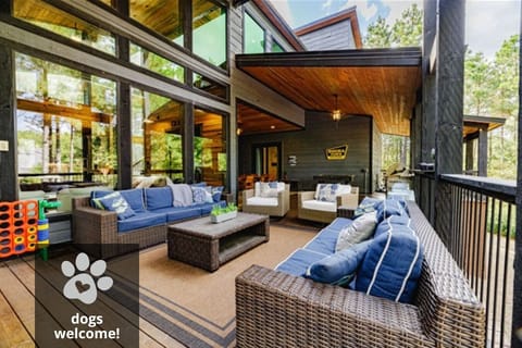 Relax on this beautifully designed cabin deck with comfortable outdoor seating, surrounded by lush nature and tall trees.