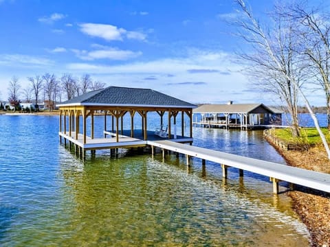 A serene lakeside dock with a covered seating area and clear waters, perfect for relaxation and enjoying scenic views.
