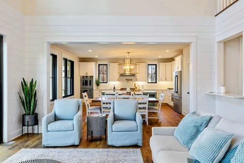 A bright and open living space with comfortable seating, high ceilings, and seamless flow into a modern kitchen and dining area.