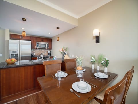 Host memorable meals in this elegant dining area featuring a polished wood table, tropical decor, and warm lighting—ideal for relaxing evenings with loved ones.