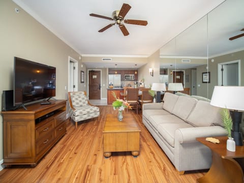 Unwind in the stylish living room featuring comfortable seating, a flat-screen TV, and a mirrored wall that adds to the spacious feel.